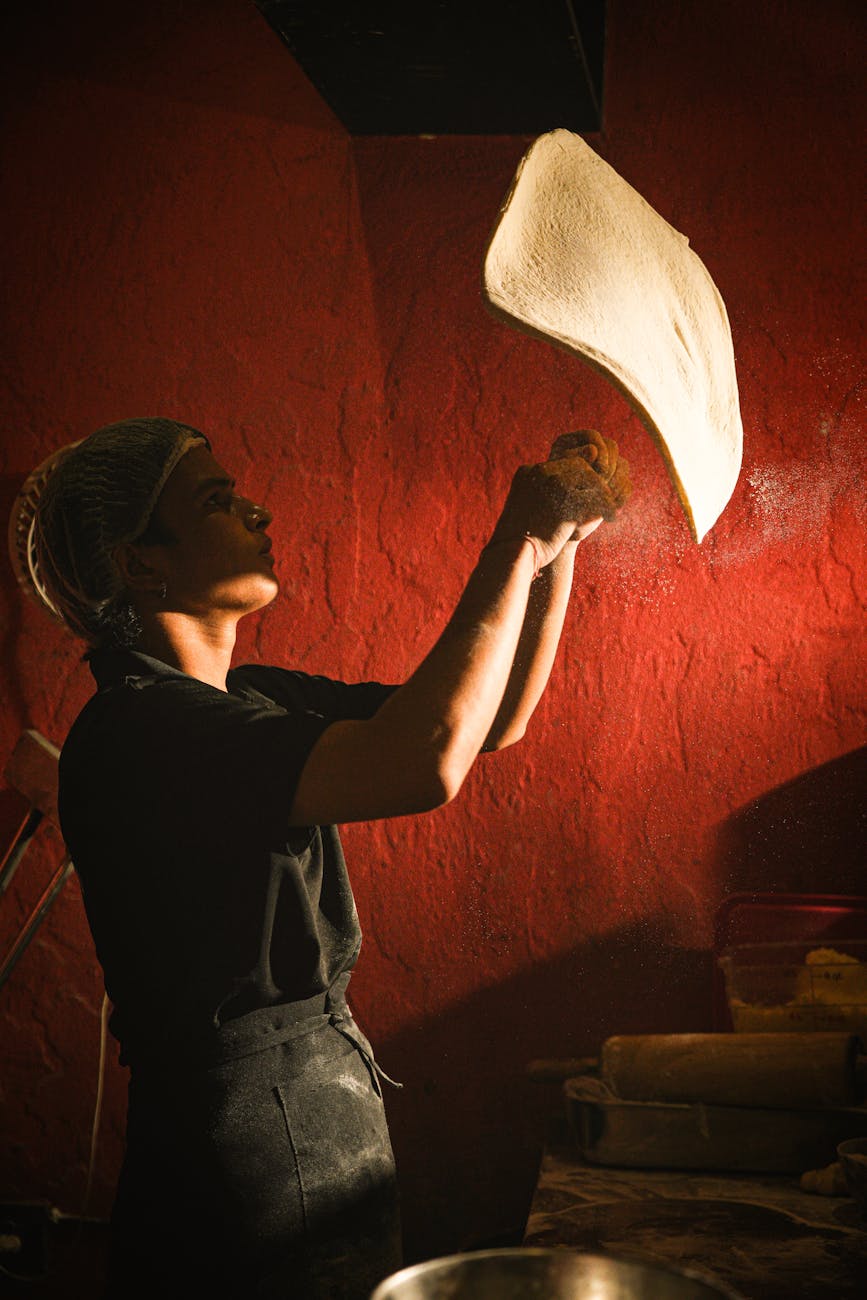 chef tossing pizza dough in traditional kitchen