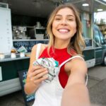 happy woman with donut taking selfie near food station